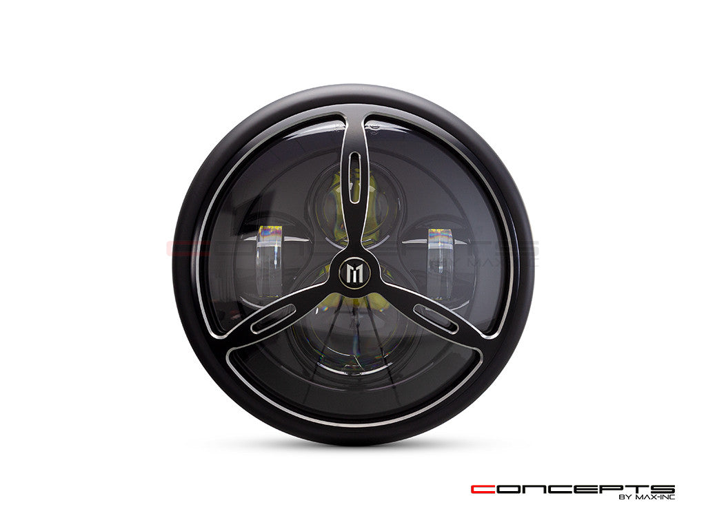 This is a photo of a motorcycle headlight, featuring a round, black casing, gold accent trim, and a bright bulb at the core, presenting a refined and durable design